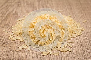 Parboiled Chinese Rice seed. Pile of grains on the wooden table. photo