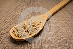 Whole Chinese Rice seed. Spoon and grains over wooden table. photo