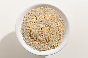 Whole Chinese Rice seed. Top view of grains in a bowl. White ba
