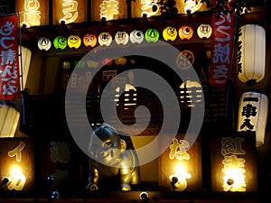 Close up picture of a golden Billiken statue and signboards of a Japanese restaurant in Osaka