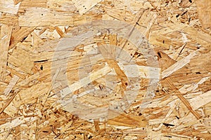 OSB boards are made of brown wood chips sanded into wooden background. Top view of OSB wood veneer background, tight