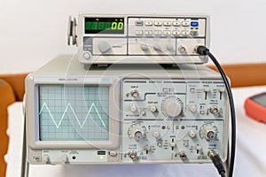 Green sine waves on the screen of a multi-button oscilloscope