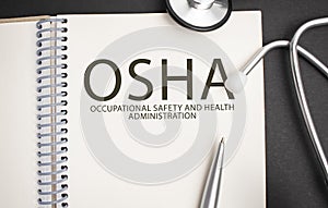 OSHA text written in a notebook lying on a desk and a stethoscope. Medical concept