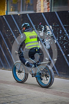 OSLO, NORWAY - MARCH, 26, 2018: Outdoor view of police man riding a bycicle in the sreets of Oslo city