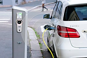 Oslo, Norway - September, 21, 2020: White electric car is charging on parking lot on electric car charging station in the street.