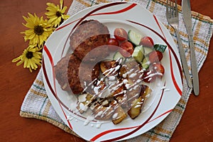 osmaÅ¾enÃ½ karbanÃ¡tek, burger na talÃ­?i s p?Ã­lohou salÃ¡t - raj?ata a okurka s americkÃ½mi bramborami photo