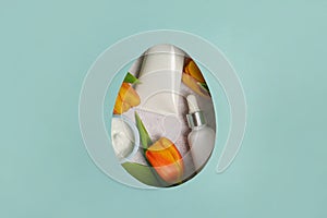 Cosmetics cream and oil with yellow tulips in an easter egg. blue background with copy space