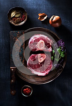 Osso buco raw steaks in a cast-iron pan, herbs and spices