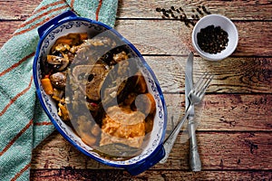 Ossobuco in cooking sauce with carrot, onion, bell pepper and mushrooms accompanied with sweet potato puree in a vintage a plate,