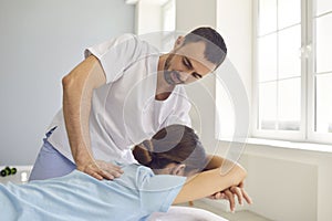 Osteopath in medical uniform fixing woman patients shoulder and back joints in manual therapy clinic