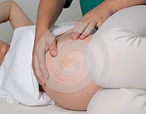 An osteopathic doctor palpates the belly of a pregnant girl in the third trimester. Preparation before childbirth