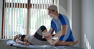 Osteopathic physician is massaging of calf muscle of female patient in modern clinic photo