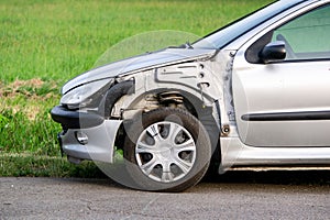 A detail of a frontal part of silver Peugeot 206 car damaged in traffic accident with missing left front fender