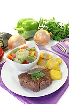 Ostrich steaks with baked potatoes and vegetables