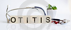 OTITIS the word is written on the wooden cubes and sthetoscope and piils . Medical concept