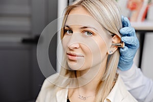 Otolaryngologist doctor checking young woman\'s ear using otoscope or auriscope at ENT clinic, close up. Hearing exam