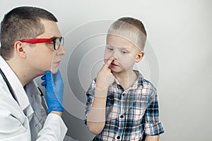 The otolaryngologist examines the boy nasal passages. Painful sensations in the nose, polyps, adenoids and shortness of breath. photo