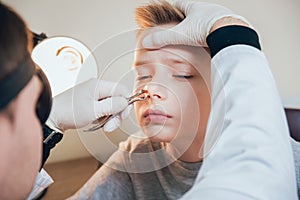 Otolaryngologist examines boy nose with nasolar dilatator.