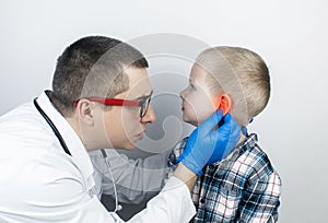 An otolaryngologist examines the ear of a boy who complains of pain. Pain relief and treatment concept. Inflammation of the ear