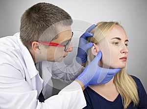 An otolaryngologist examines the ear of a girl who complains of pain. Pain relief and treatment concept. Inflammation of the ear