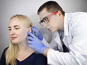 An otolaryngologist examines the ear of a girl who complains of pain. Pain relief and treatment concept. Inflammation of the ear