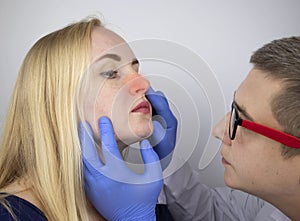 The otolaryngologist examines the girl`s nasal passages. Painful sensations in the nose, polyps, adenoids and shortness of breath