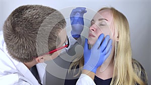 The otolaryngologist examines the girl`s nasal passages. Painful sensations in the nose, polyps, adenoids and shortness of breath.