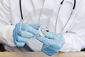 An otolaryngologist holds a hearing aid in his hands. The doctor consults the patient