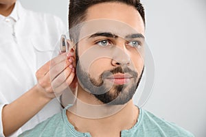 Otolaryngologist putting hearing aid in man`s ear