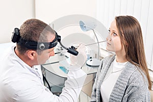 Otolaryngologist. Very attentive medical worker looking at nose of his visitor