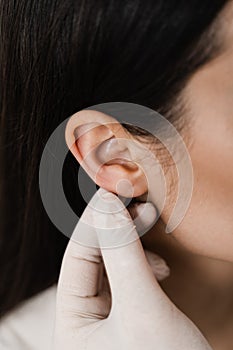 Otoplasty ear surgery close-up. Surgeon doctor examines girl ears before otoplasty cosmetic surgery. Otoplasty surgical