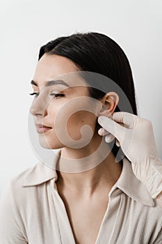 Otoplasty ear surgery. Otoplasty surgical reshaping of pinna and ear. Surgeon doctor examines girl ears before otoplasty