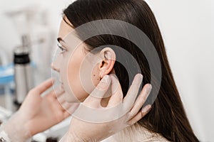 Otoplasty surgical reshaping of pinna and ear. Otoplasty ear surgery. Surgeon doctor examines girl ears before otoplasty