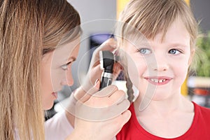 Otorhinolaryngologist conducts medical examination of little girl ear photo