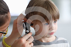 Otorhinolaryngologist examines little girl`s ear with otoscope in clinic