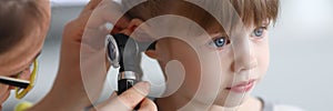 Otorhinolaryngologist examines little girl`s ear with otoscope in clinic