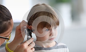 Otorhinolaryngologist examines little girl's ear with otoscope in clinic