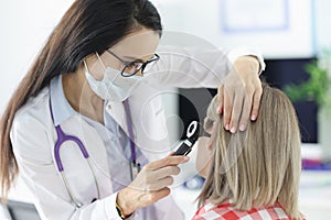 Otorhinolaryngologist examining patients sore ear with otoscope in clinic photo