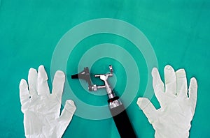Otoscope  with gloves on green surgery background in ENT medical healthcare concept with copy space