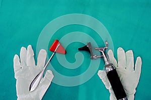 Otoscope and hammer jerk with gloves on green surgery background in ENT medical healthcare concept with copy space