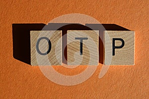 OTP, On The Phone, in 3d wooden alphabet letters isolated on orange background photo