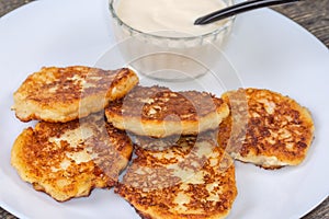 Ð¡ottage cheese pancakes with sour cream on dish close-up