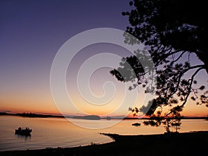 Ottawa River sunset with boat and tree silhouette