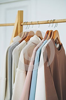 Ð¡otton tops sweatshirts in natural tones on wooden shelf in bright room