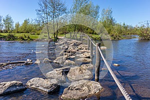 Oude Maas river with stepping stones used as a bridge at Brug Molenplas, wooden posts and rope fences