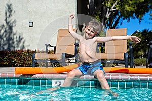 Oudoor summer activity. Concept of fun, health and vacation. Boy eight years old sits near a pool in hot summer day.