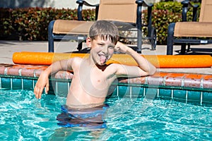 Oudoor summer activity. Concept of fun, health and vacation. Boy eight years old sits in a pool in hot summer day.