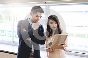 Oung business man and woman standing near windows to discussion
