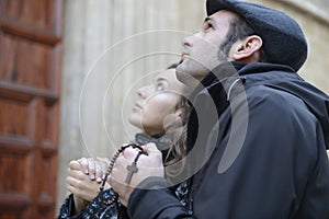Oung couple praying to god using prayer beads