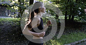 oung fitness sports women runner running in the park. Happy athletic woman listening music on earphones while running in